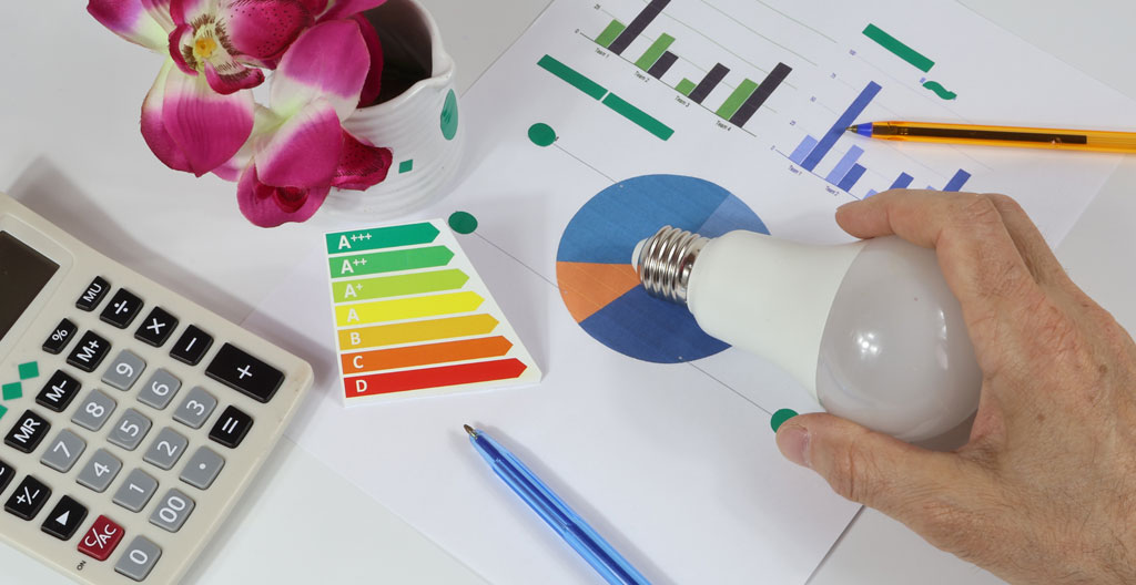 Conseiller en efficacité énergétique avec tablette numérique assis à table de cuisine avec couple de propriétaires québécois, documents d'évaluation énergétique et plan de maison visibles, discussion collaborative dans intérieur résidentiel contemporain